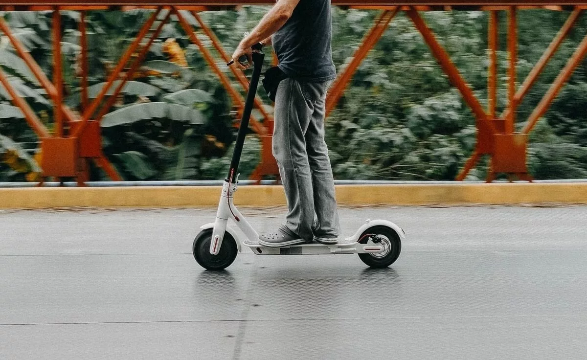 Person, die einen Elektroroller fährt, auf einem Gehweg oder einer Straße - GPS Tracker E-Scooter